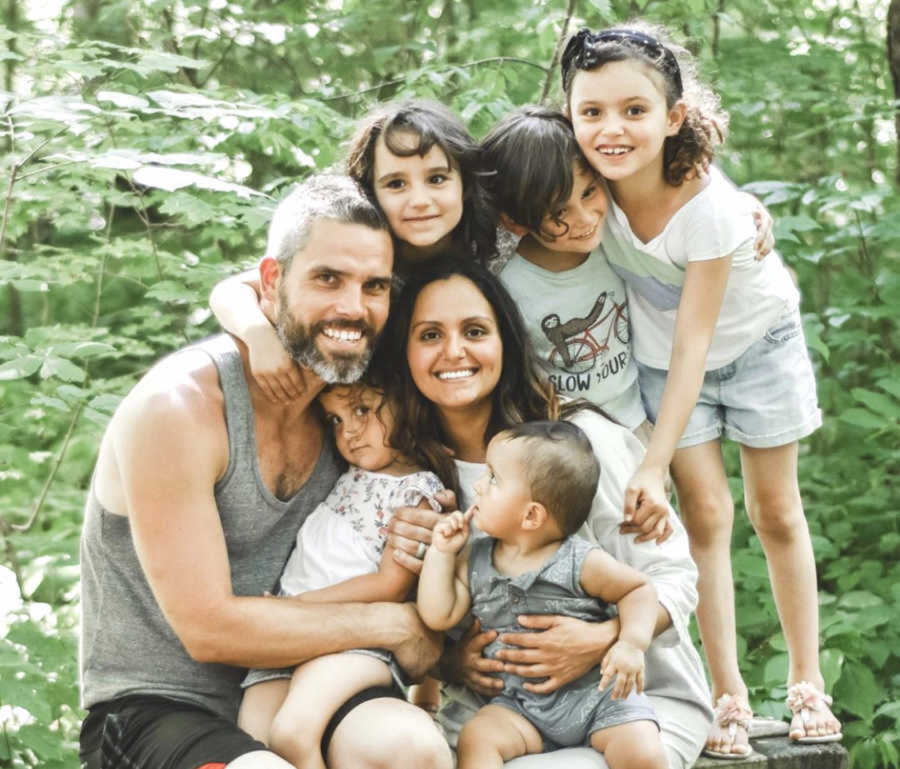 husband and wife sit outdoors with their 5 children