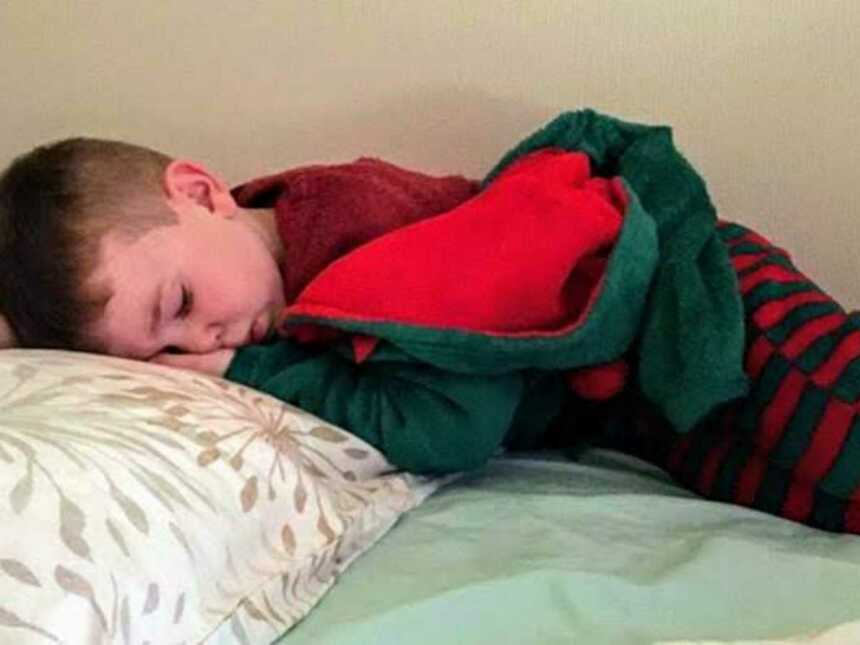 Little boy sleeping on bed in Christmas pajamas