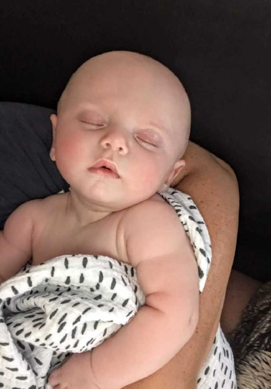 Sleeping baby boy being held in white dotted blanket