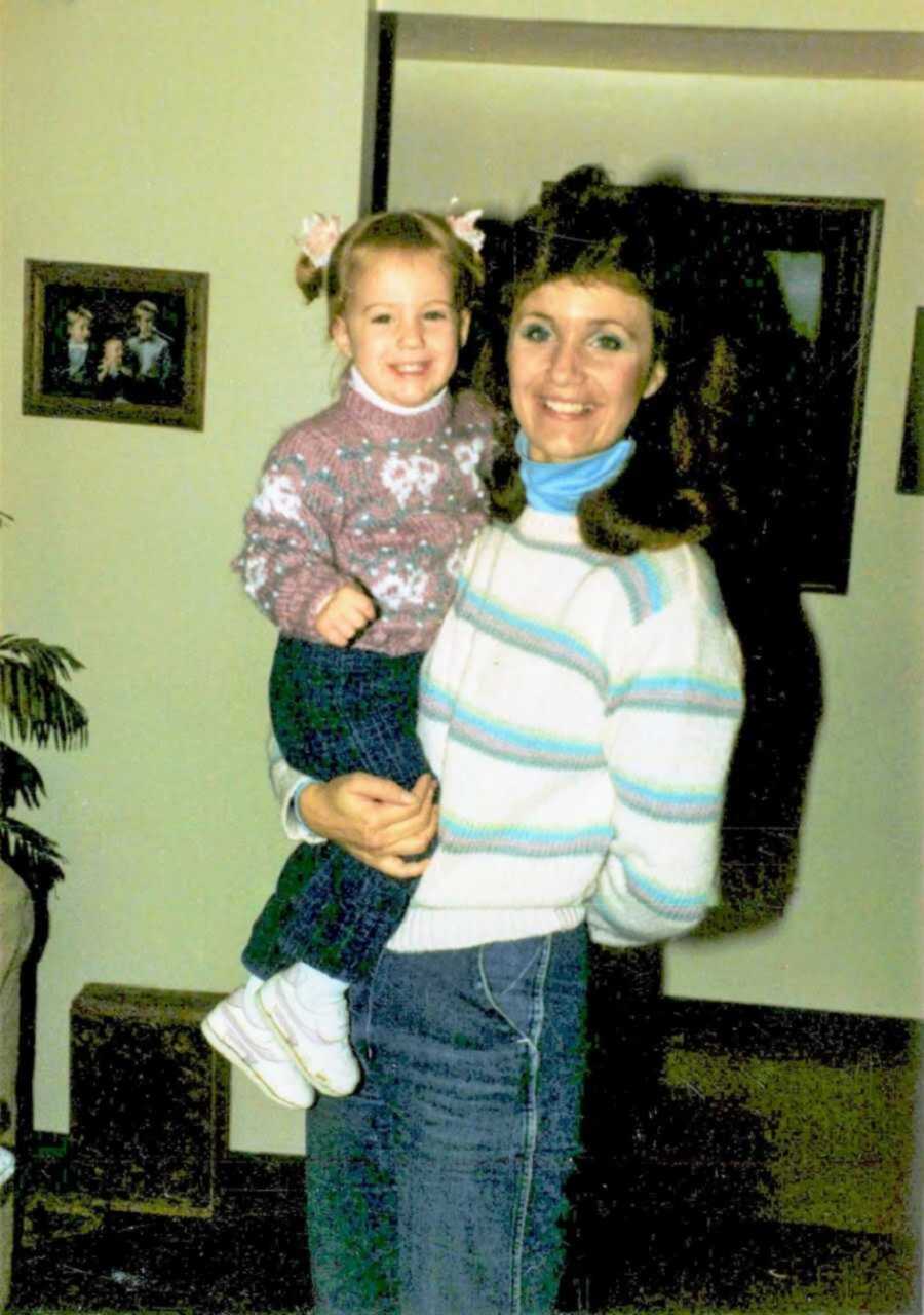 Joyful mom holding her smiling toddler daughter in a sweater