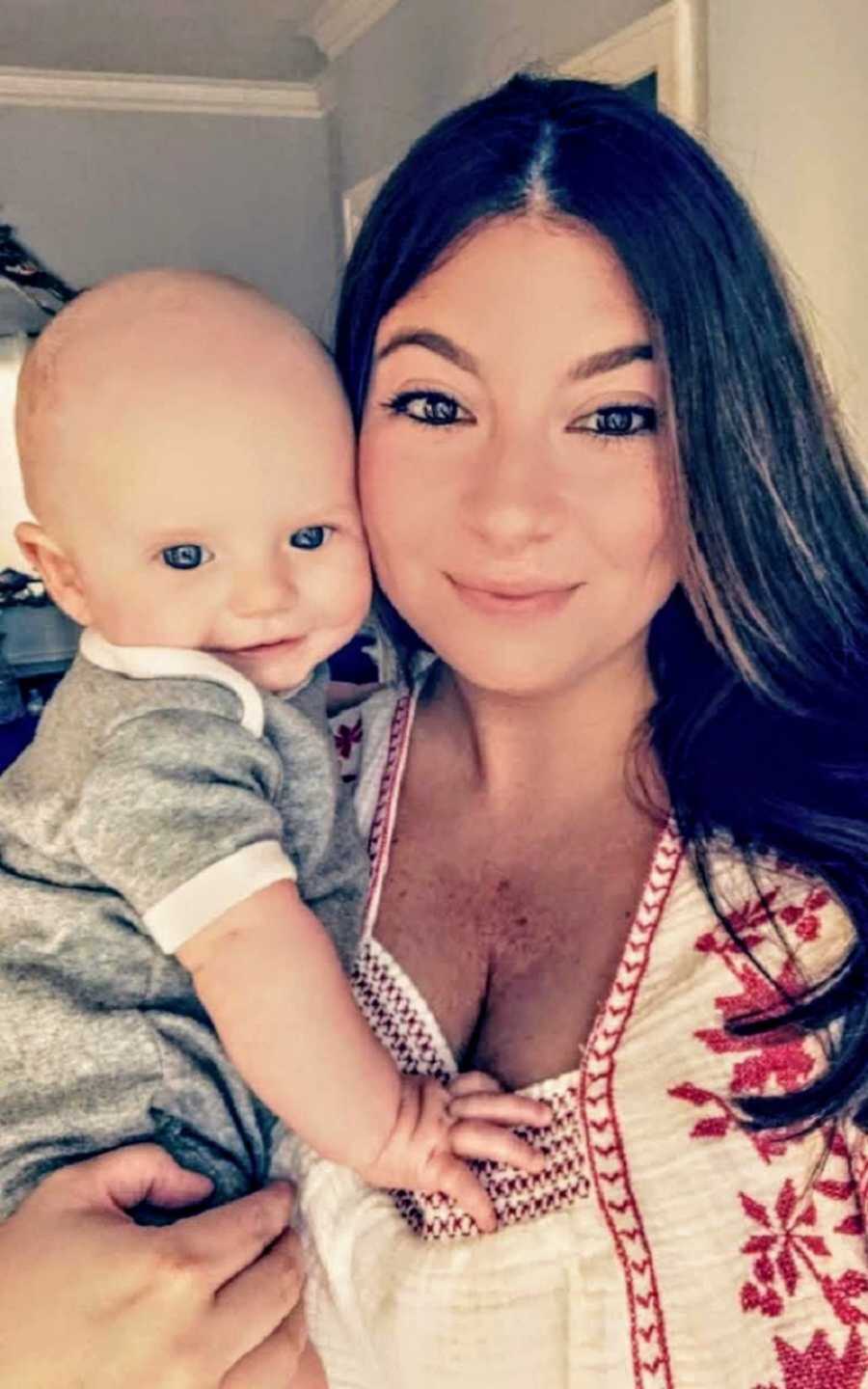 Foster mom smiling holding a bright blue eyed baby boy