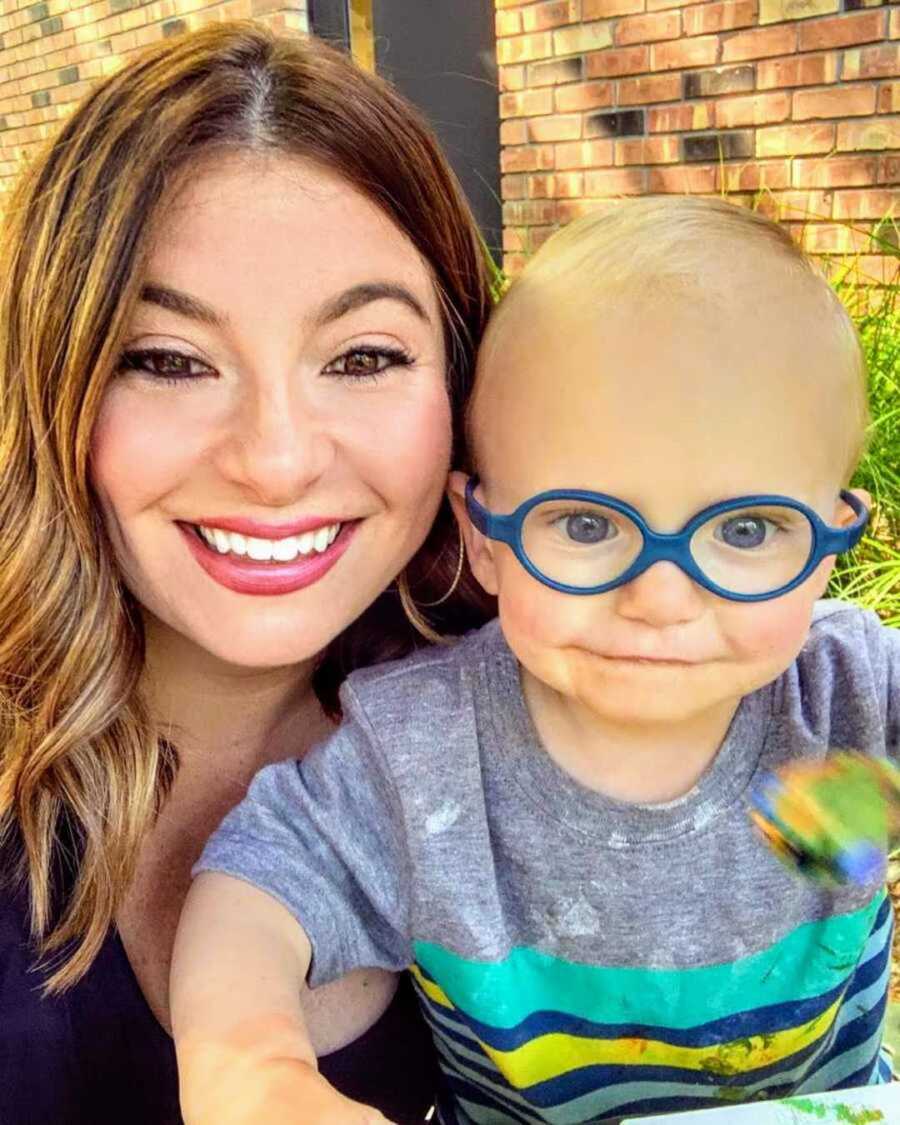 Smiling new mom with adopted son in glasses and blue shirt