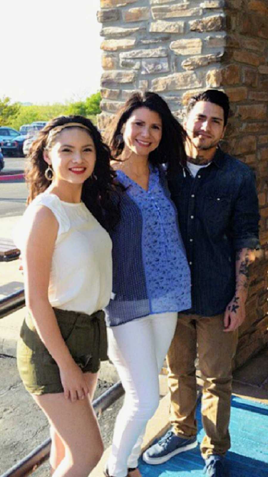 Mom in blue blouse smiling next to daughter and son