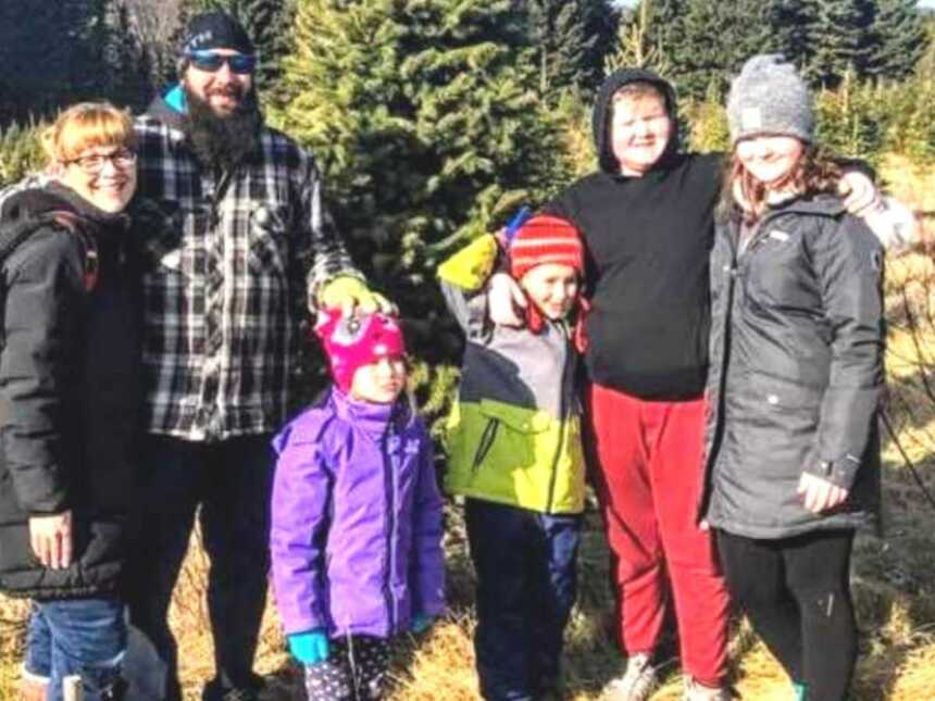 Family standing together in Christmas tree farm