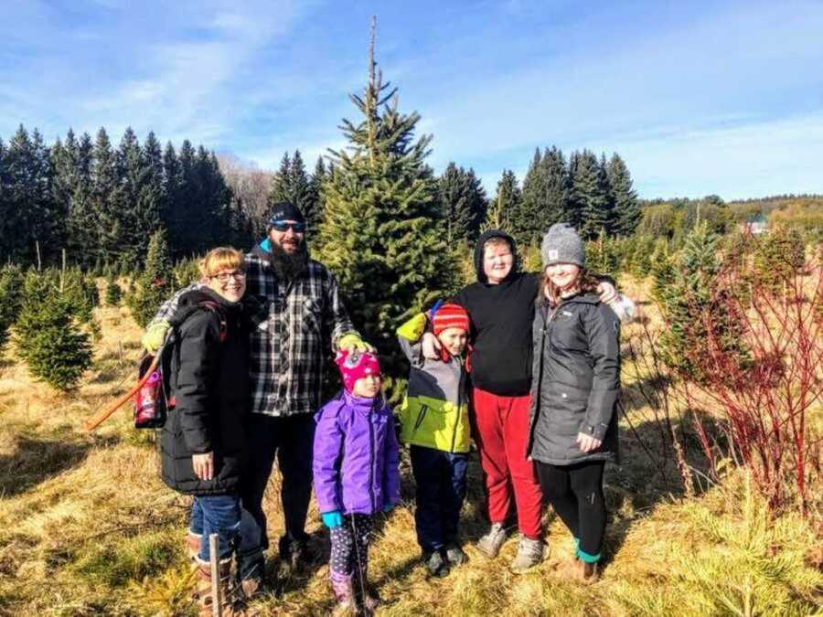 Family standing in grass at Christmas tree farm