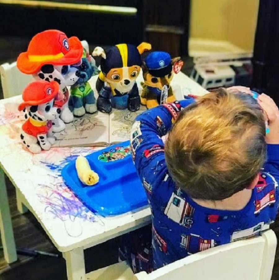 Little boy eating food next to Paw Patrol toys