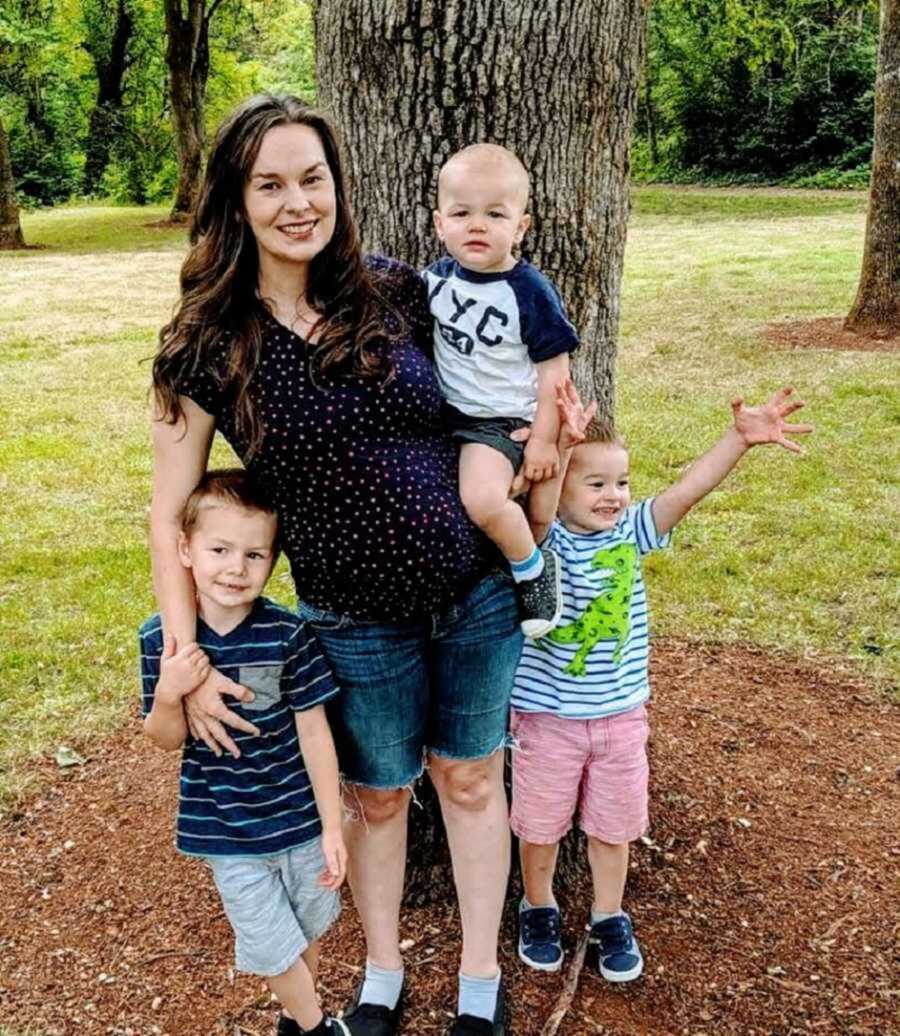 Mom and three kids smiling in front of tree