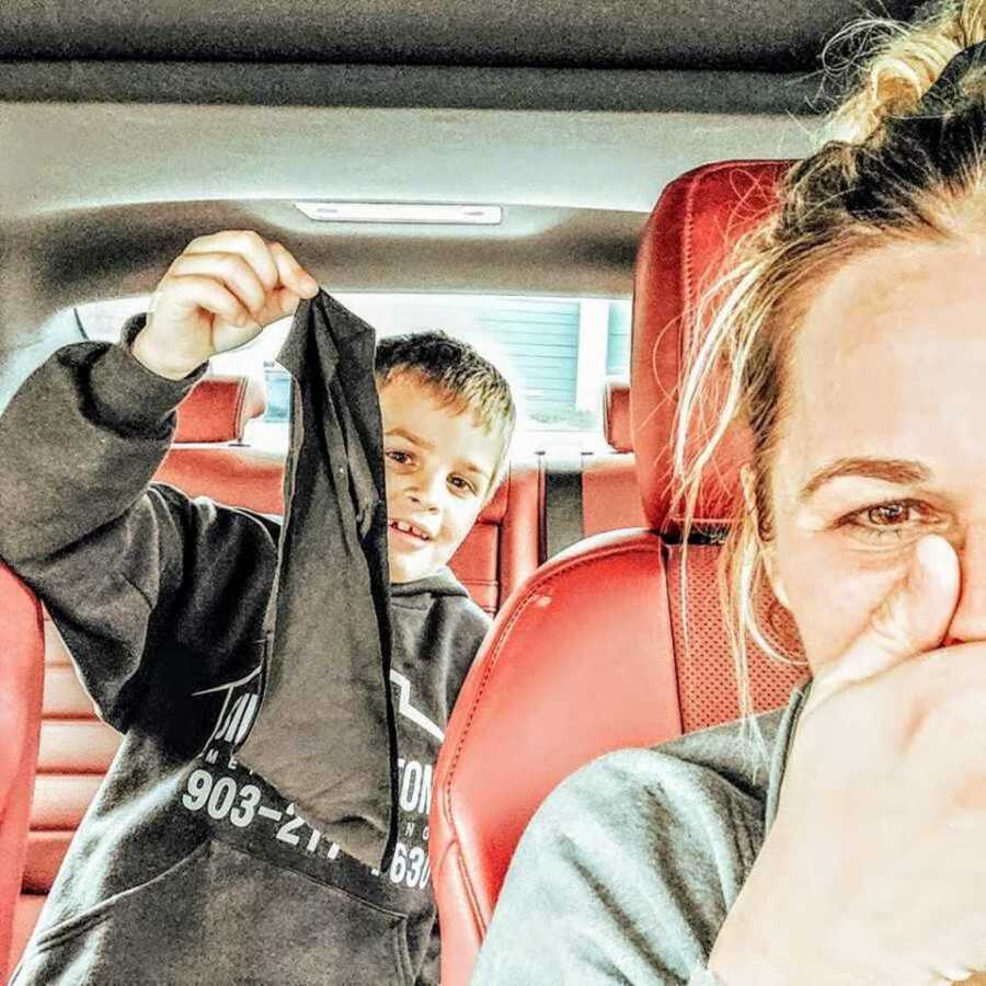 Boy holding up black underwear inside car