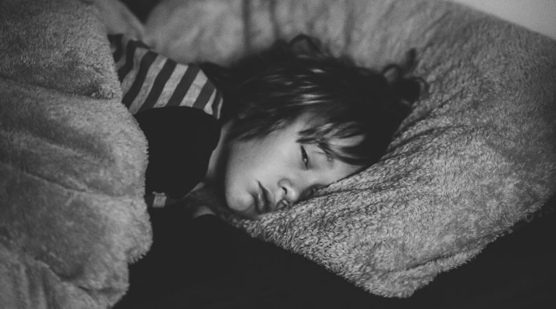 young boy lays sick in bed with the flu