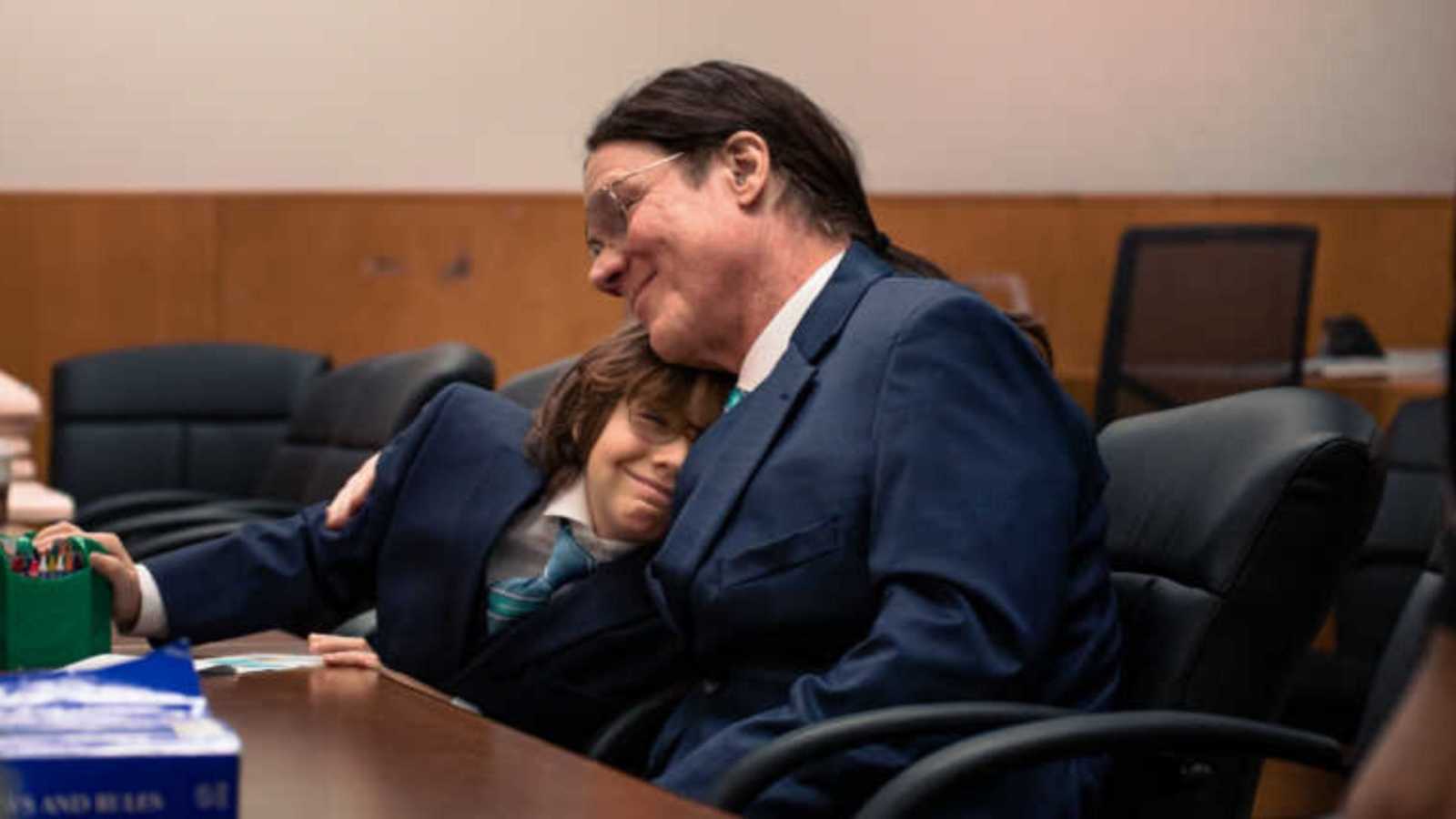 Adoptive father and son smiling and hugging in courtroom