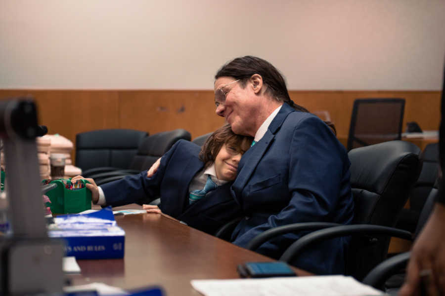 Adoptive dad and son happily embracing in courtroom