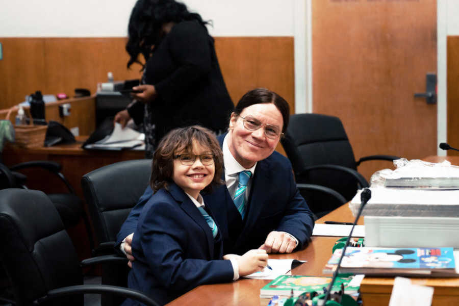 Father and son in matching suits smiling in courtroom