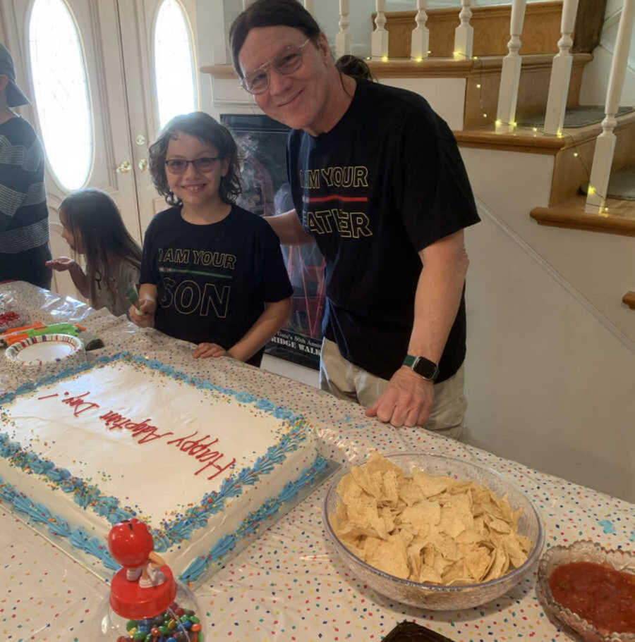 Adoptive dad and son smiling next to cake and tortilla chips