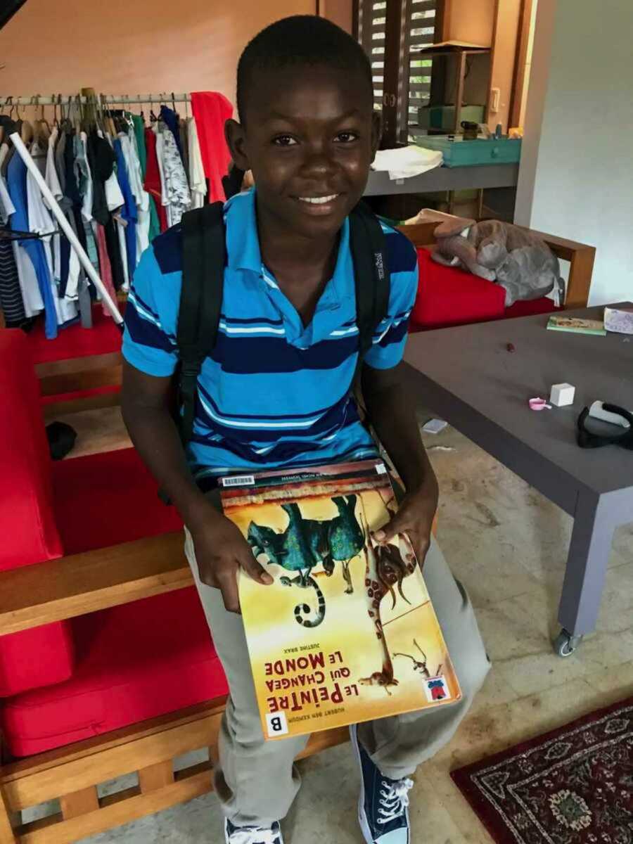 haitian boy smiles and holds book