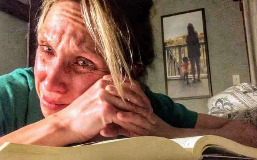 Crying mom praying over open book
