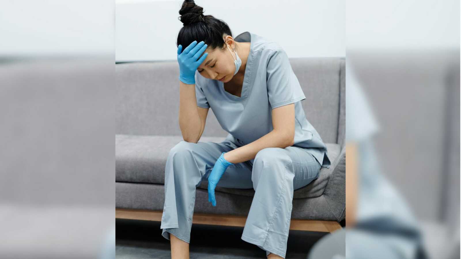 nurse sits tired with head in hand