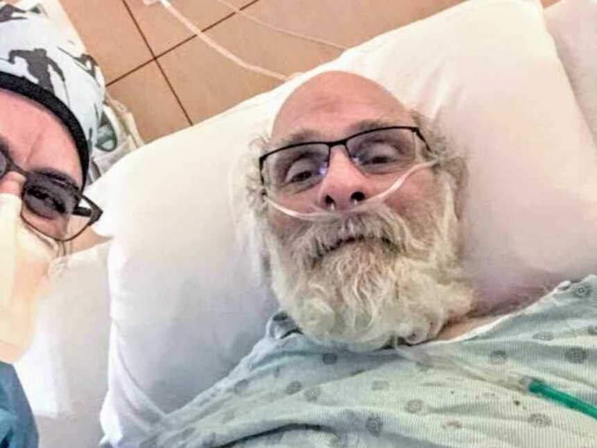 Emergency medicine physician smiling next to Covid-19 survivor in hospital bed