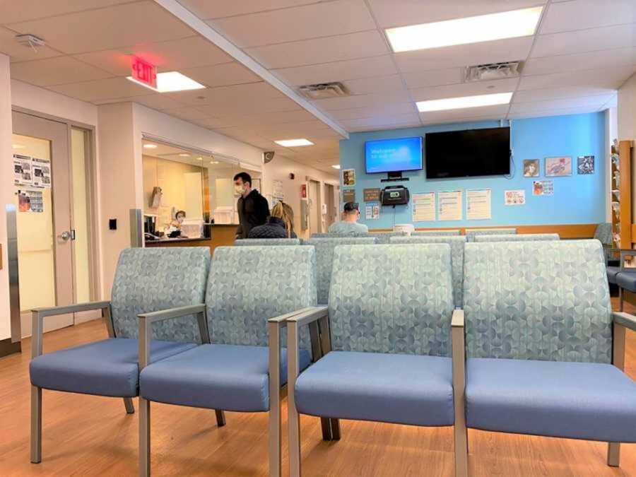 Row of blue chairs in bright hospital waiting room