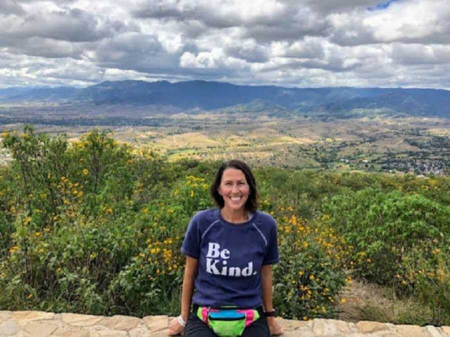 woman sits outside in "be kind." shirt