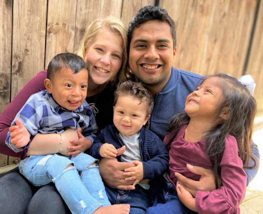 Adoptive parents embracing three children 
