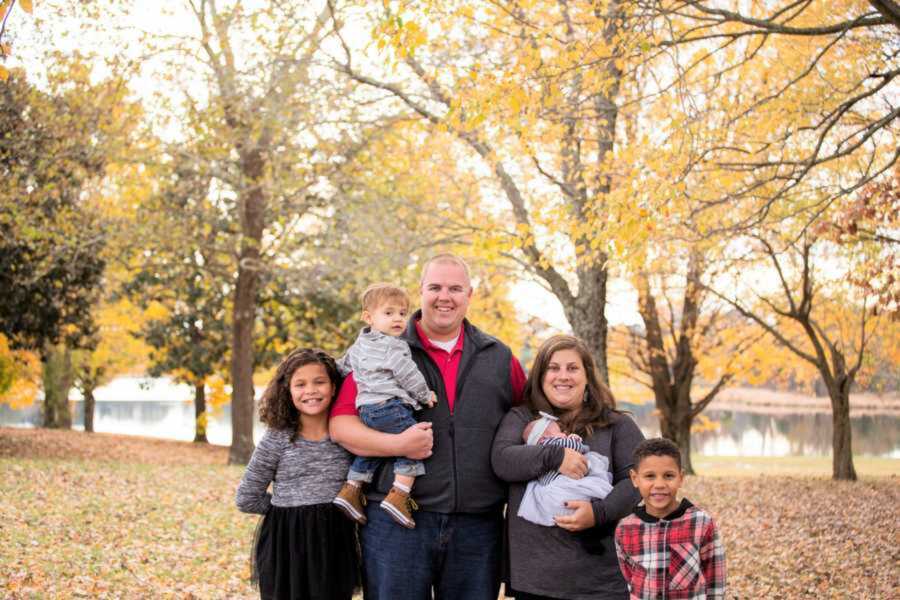 Foster family smiling in leafy field