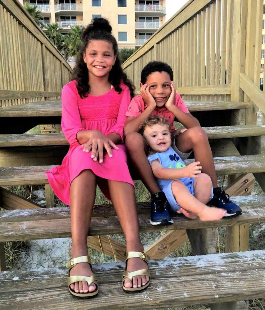 Foster siblings smiling on top of wooden staircase