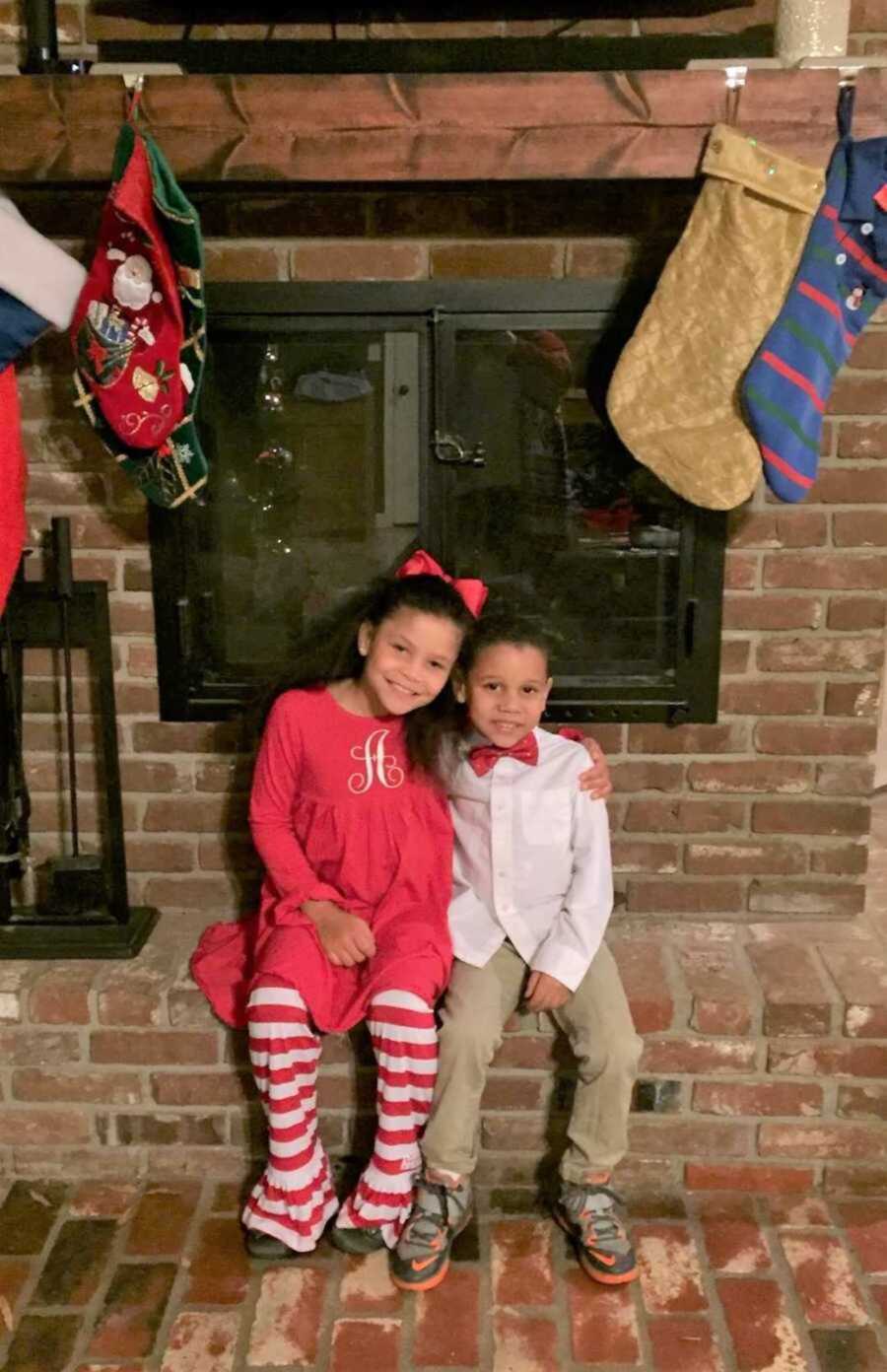 Foster siblings smiling next to fireplace