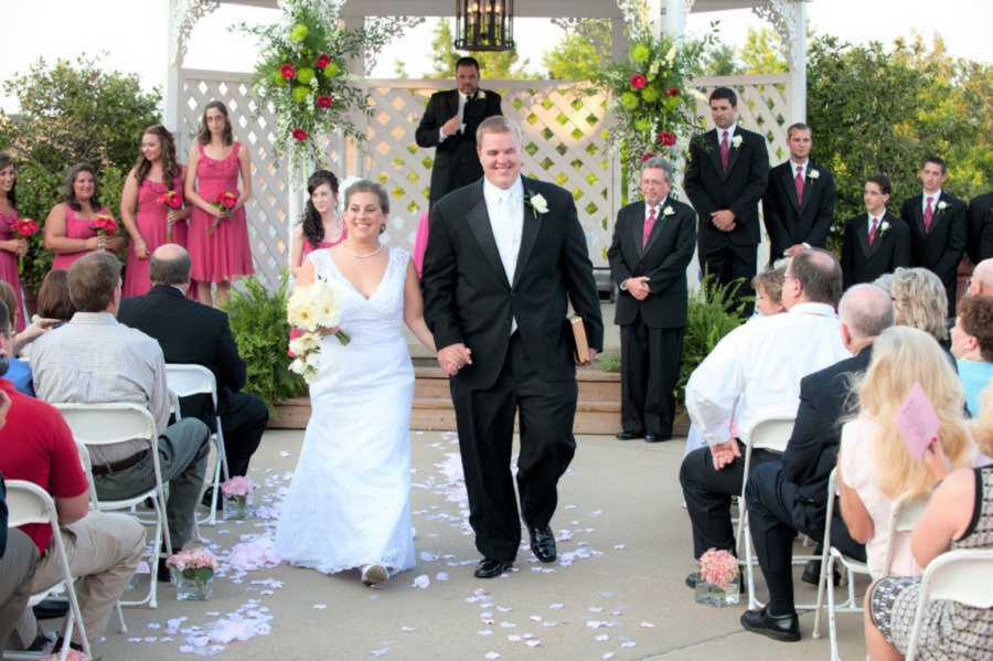 Bride and groom smiling while walking down wedding aisle