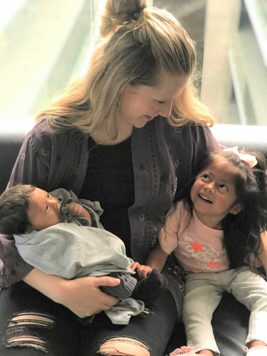 Blonde adoptive mom holding newborn and toddler