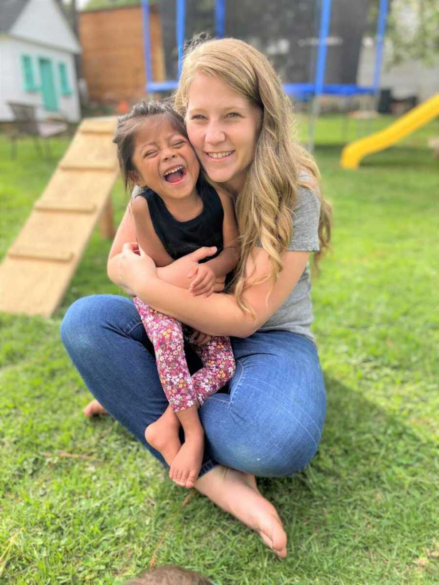 Mom embracing special needs daughter on grassy lawn