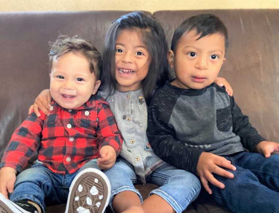 Three siblings posing on brown leather couch