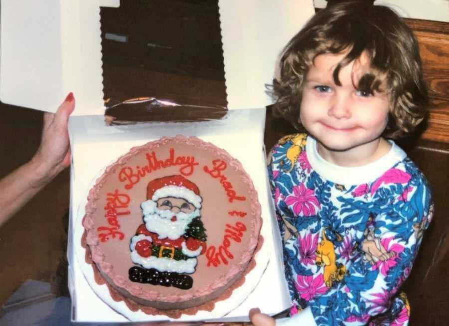 Little girl smiling while holding Santa birthday cake