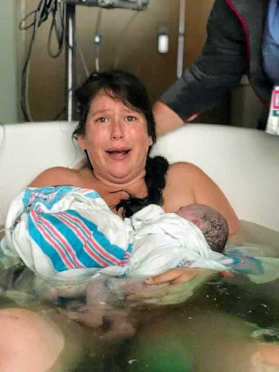 Crying mom holds newborn twins in arms