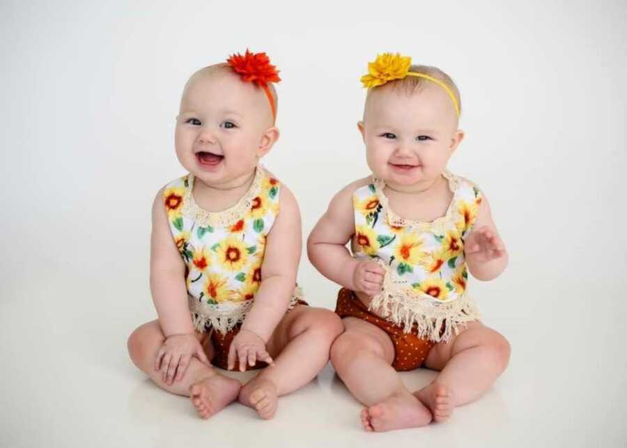 infant twin girls wearing matching flower outfits