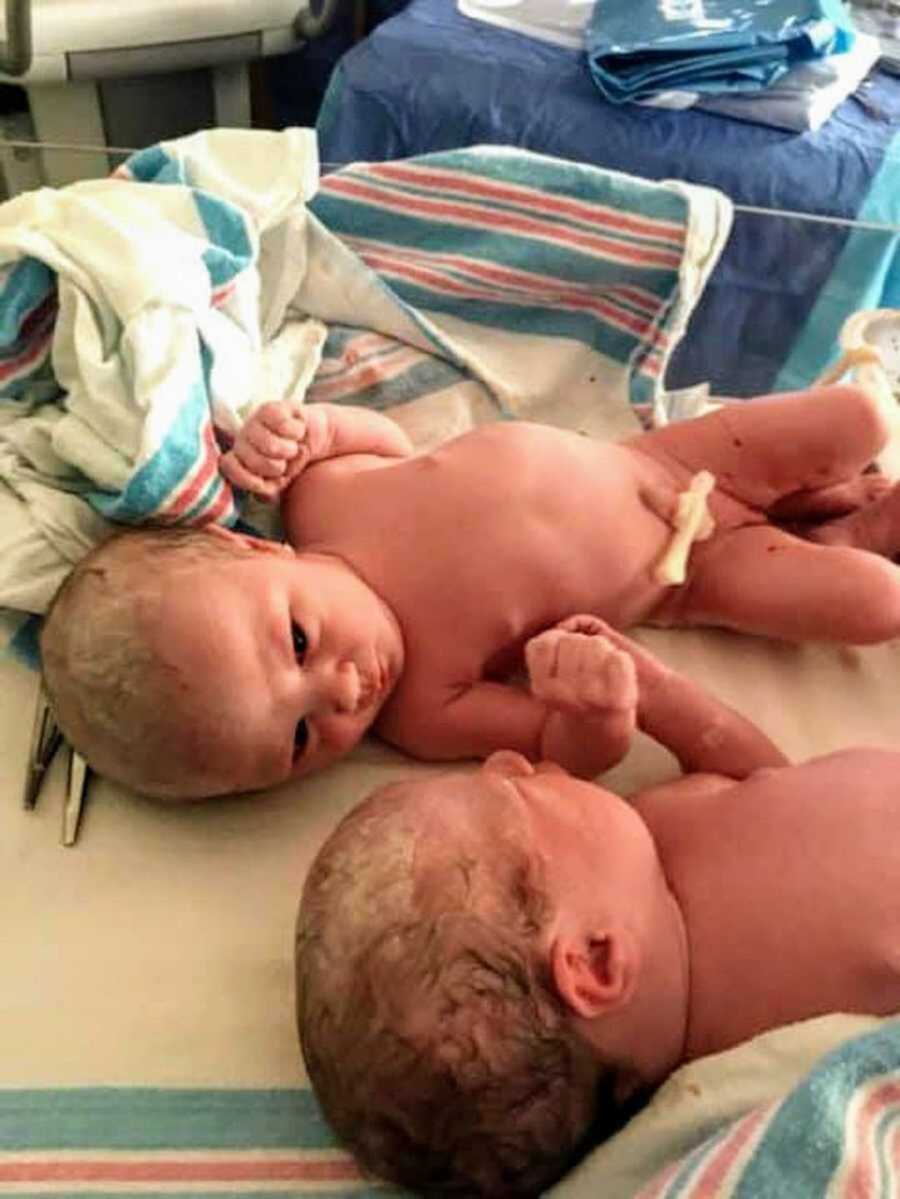 Twin newborn girls lying on hospital blankets