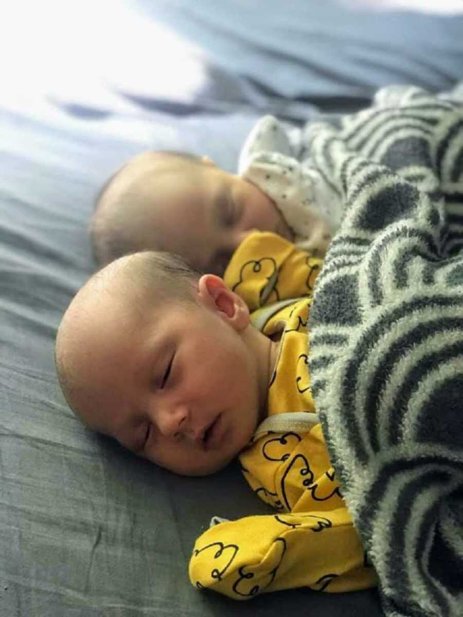 Sleeping newborn twin girls under blanket