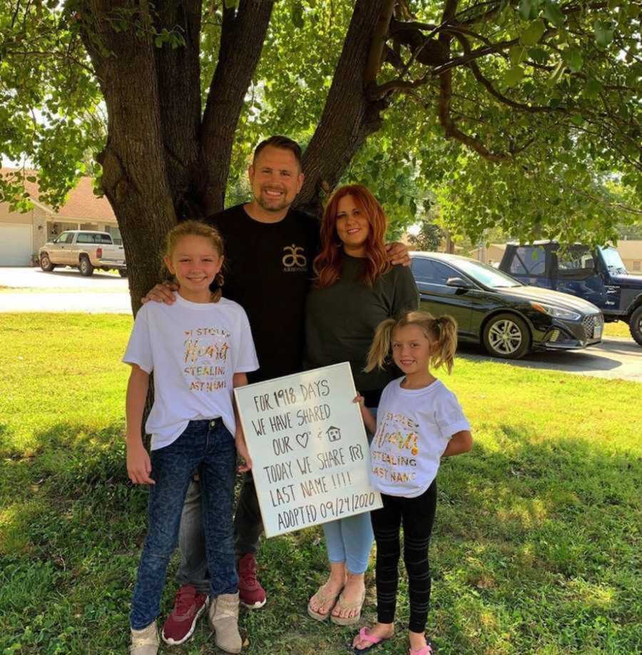 Adoptive family smiling together in front of tree