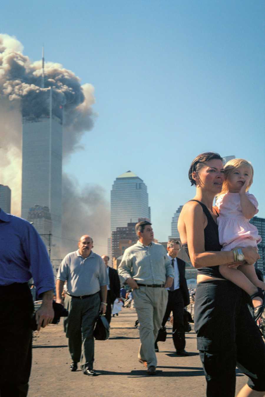 Woman holds her baby as she watches the towers in disbelief
