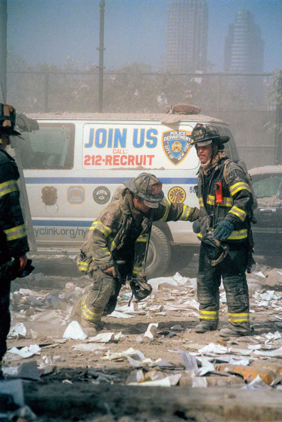 A fireman assists another firefighter as they stand in the debris of the crash