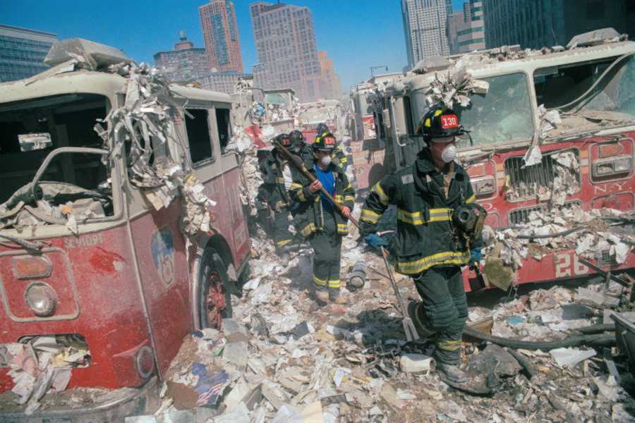 Firefighters walking amongst firetrucks and debris