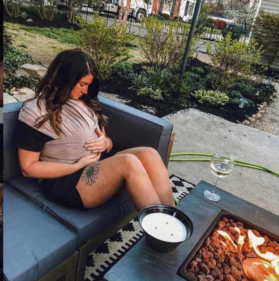 Foster mom holding newborn girl on chest in front of backyard fire pit