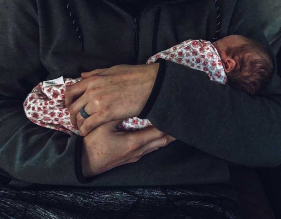 Foster dad in gray sweater holding newborn baby