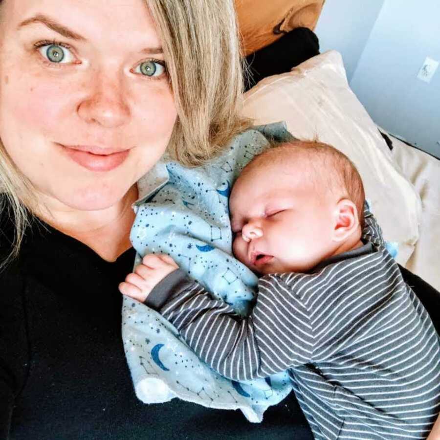 Big sister smiling while holding newborn nephew