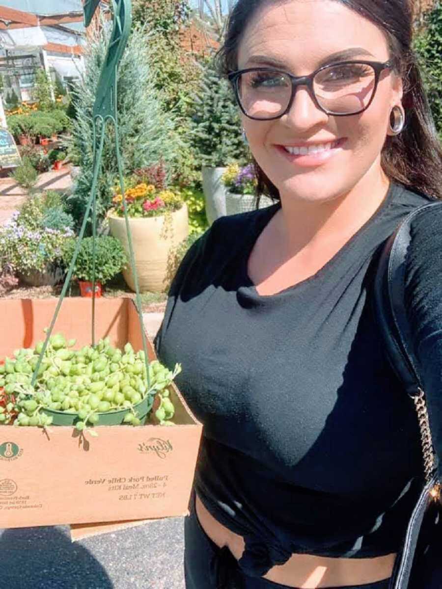 mom taking a selfie in a plant store with a plant she is buying