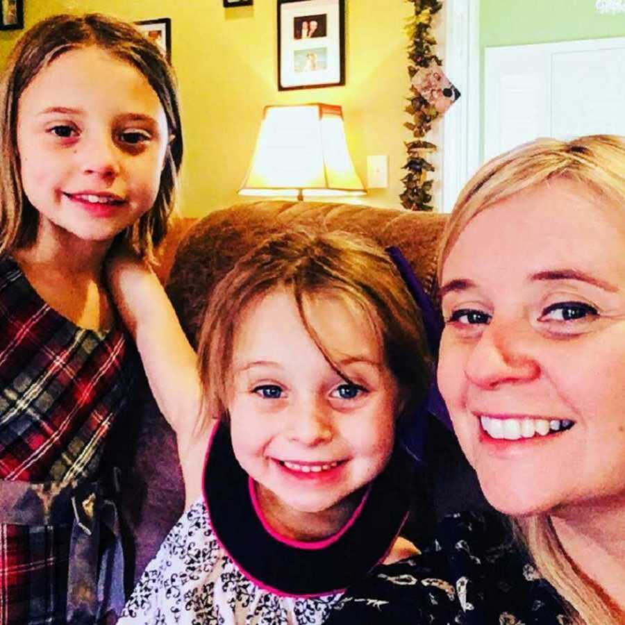 mom taking a selfie with her two daughters sitting in a chair