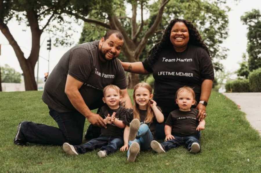 Adoptive family posing in grassy field