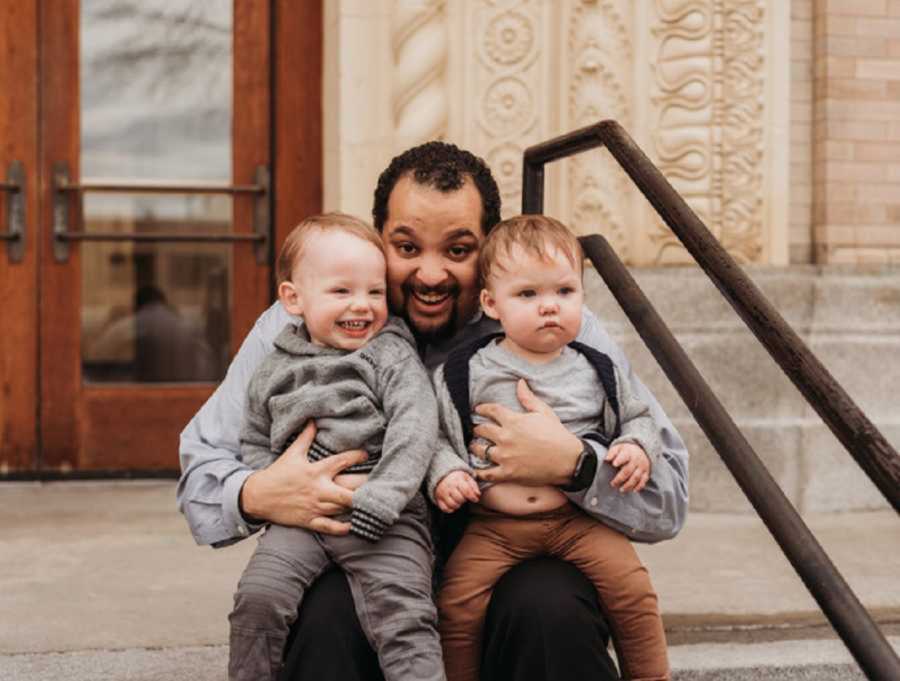 Adoptive father holding two sons outside courtroom