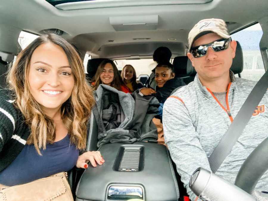 Foster family smiling together inside car