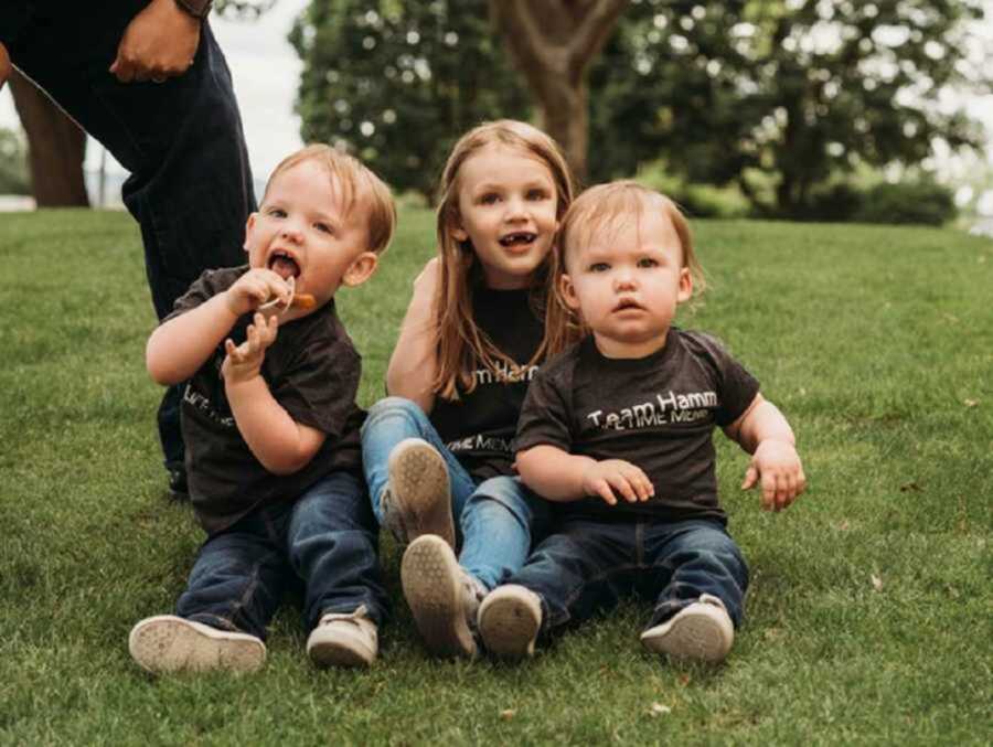 Three foster kids sitting on grassy field