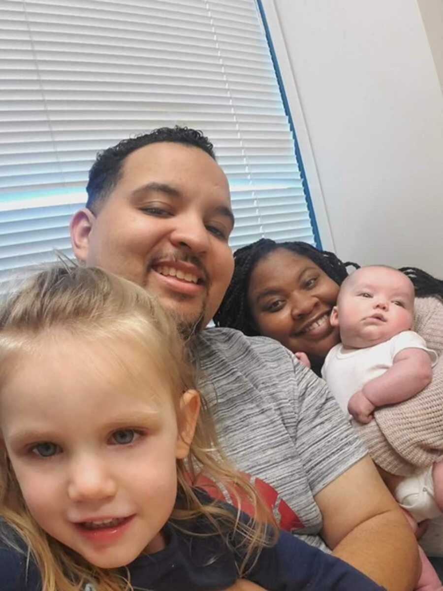 Foster parents posing with two kids in front of window